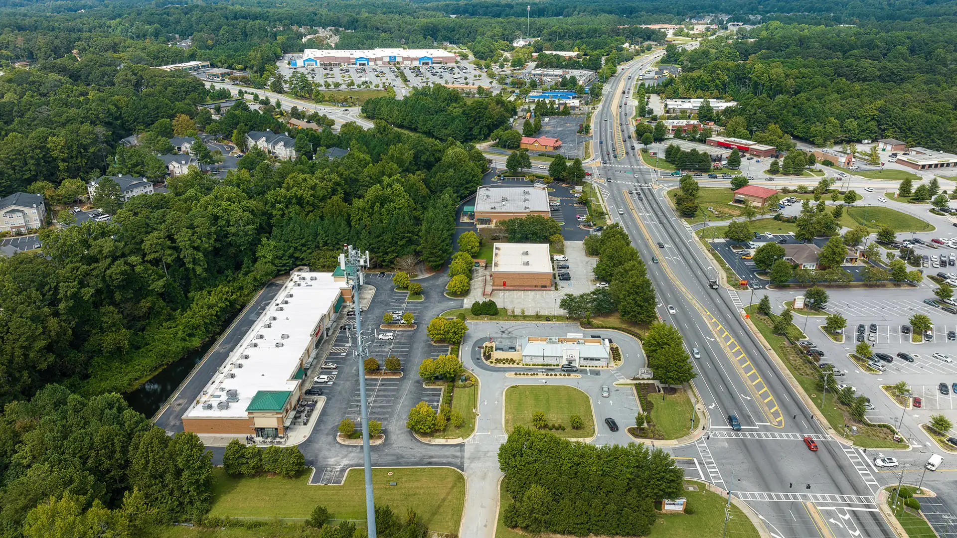 Aerial view of a commercial corridor with small retail and flex buildings along a main road.