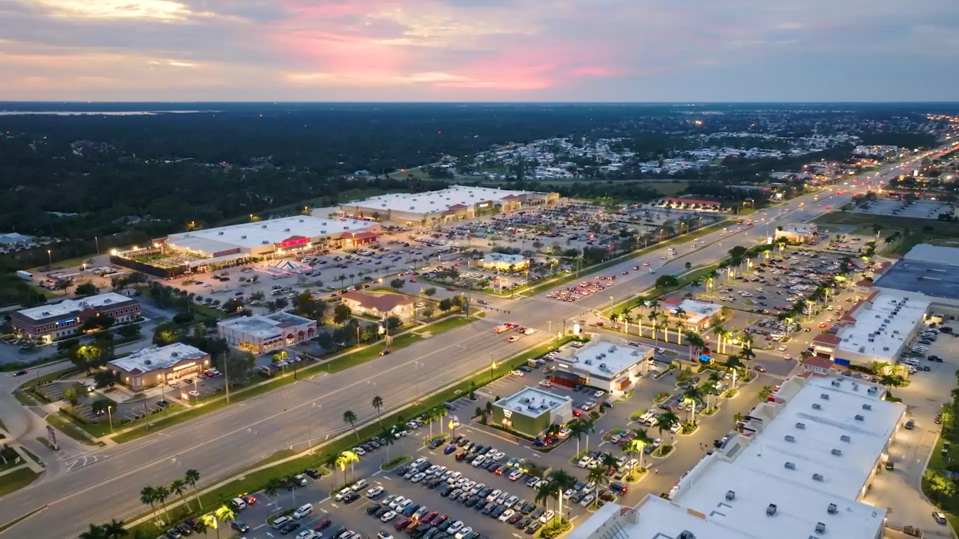 Aerial view at sunset of a commercial corridor with retail centers, flex buildings and full parking lots.